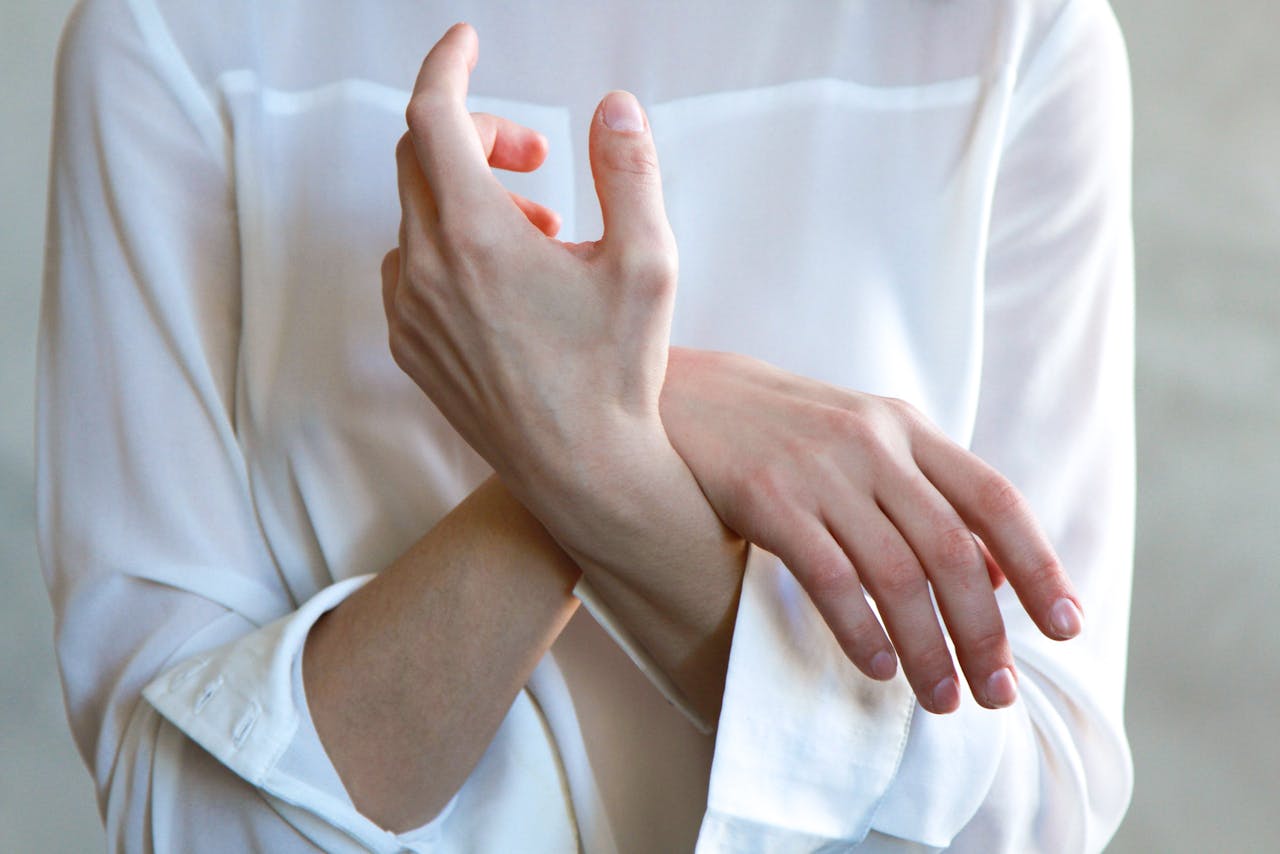 Elegant hands in a white shirt gently touching each other, symbolizing calm and tenderness.
